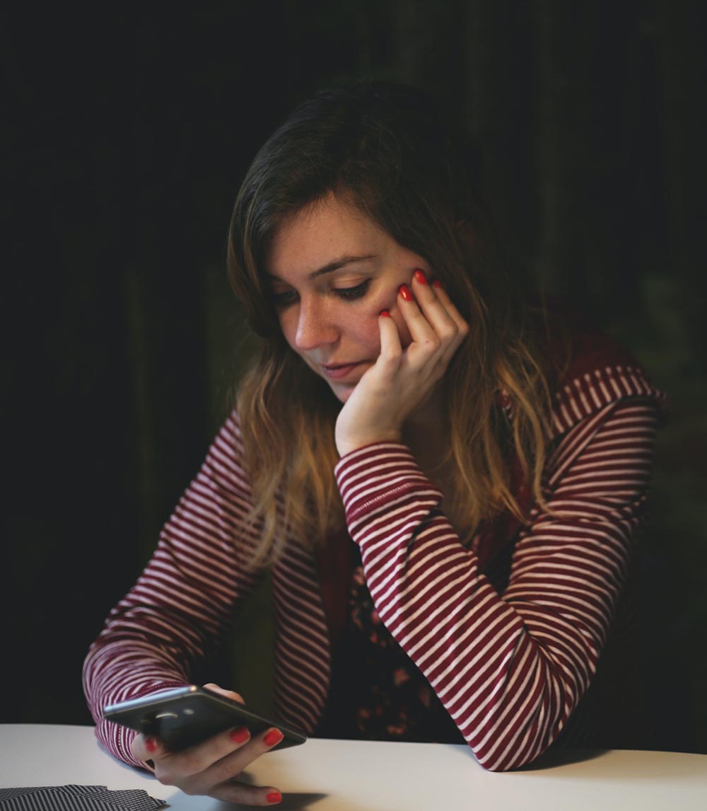 Woman sitting at a table looking at her cell phone